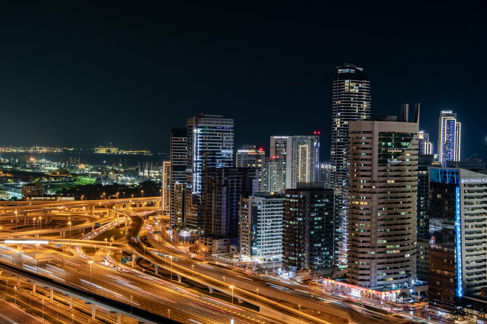 Vibrant night view of Dubai's modern skyline with illuminated skyscrapers and bustling highways.
