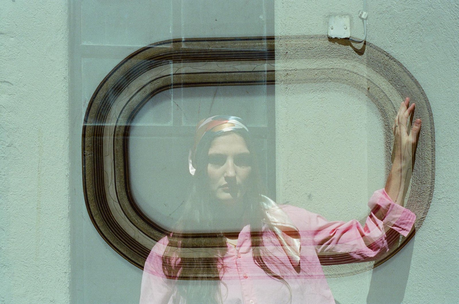 Creative double exposure of a woman in pink blending with an abstract frame.