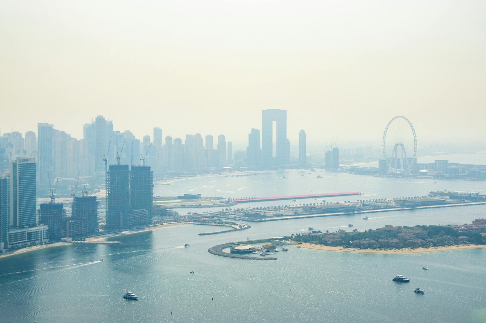 Scenic aerial view of Dubai Marina skyline and Persian Gulf on a hazy day.
