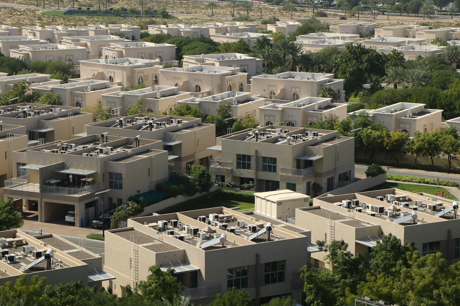 Aerial view of modern residential villas surrounded by greenery in Dubai.