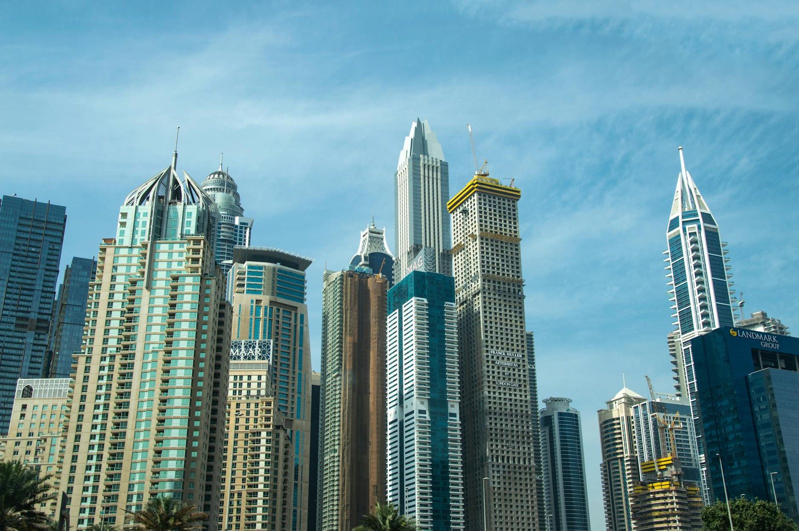 Modern skyscrapers against a blue sky in Dubai's bustling cityscape.