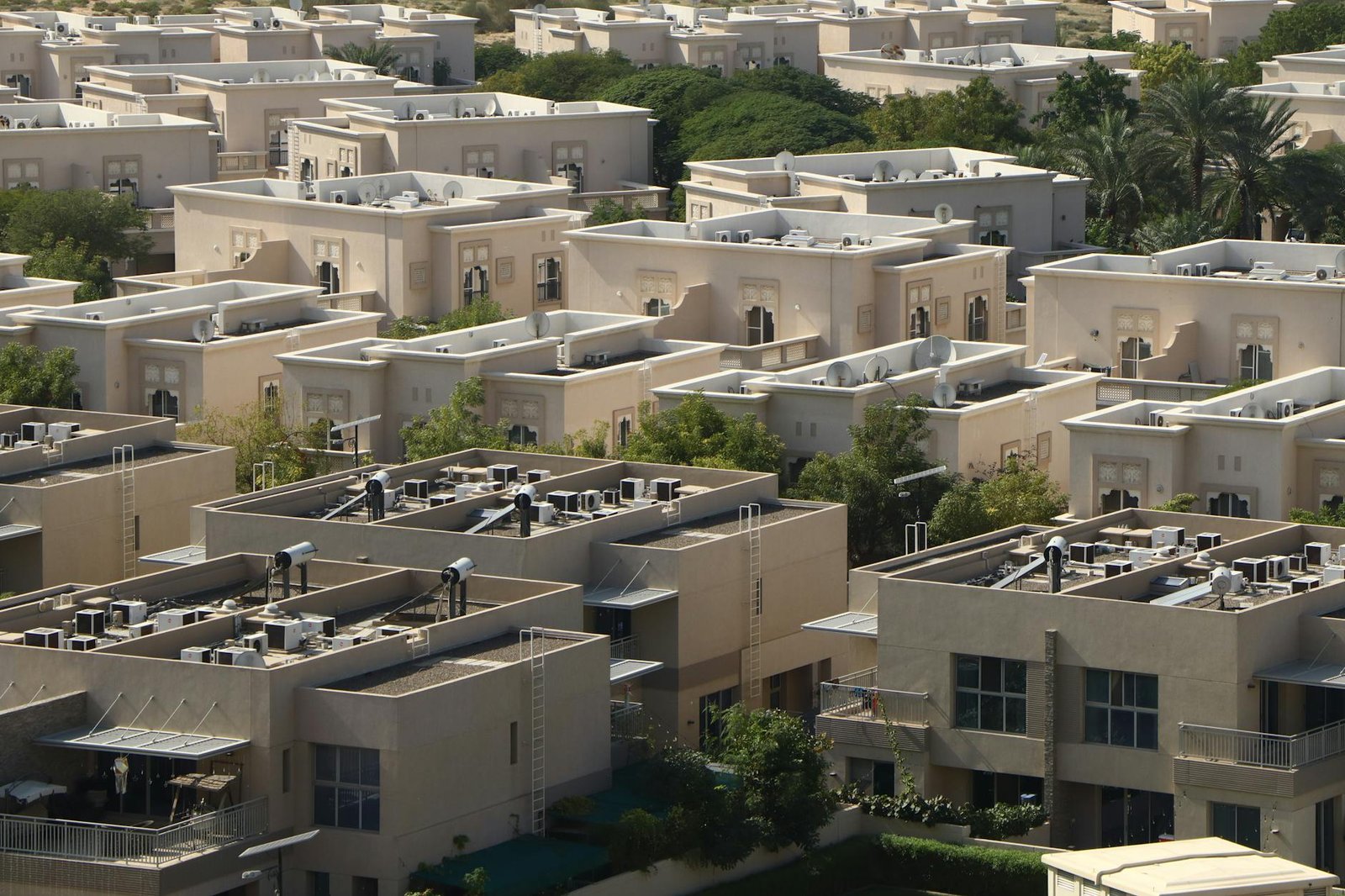 Aerial photo of Dubai's residential area showcasing uniform, modern architecture amid greenery.