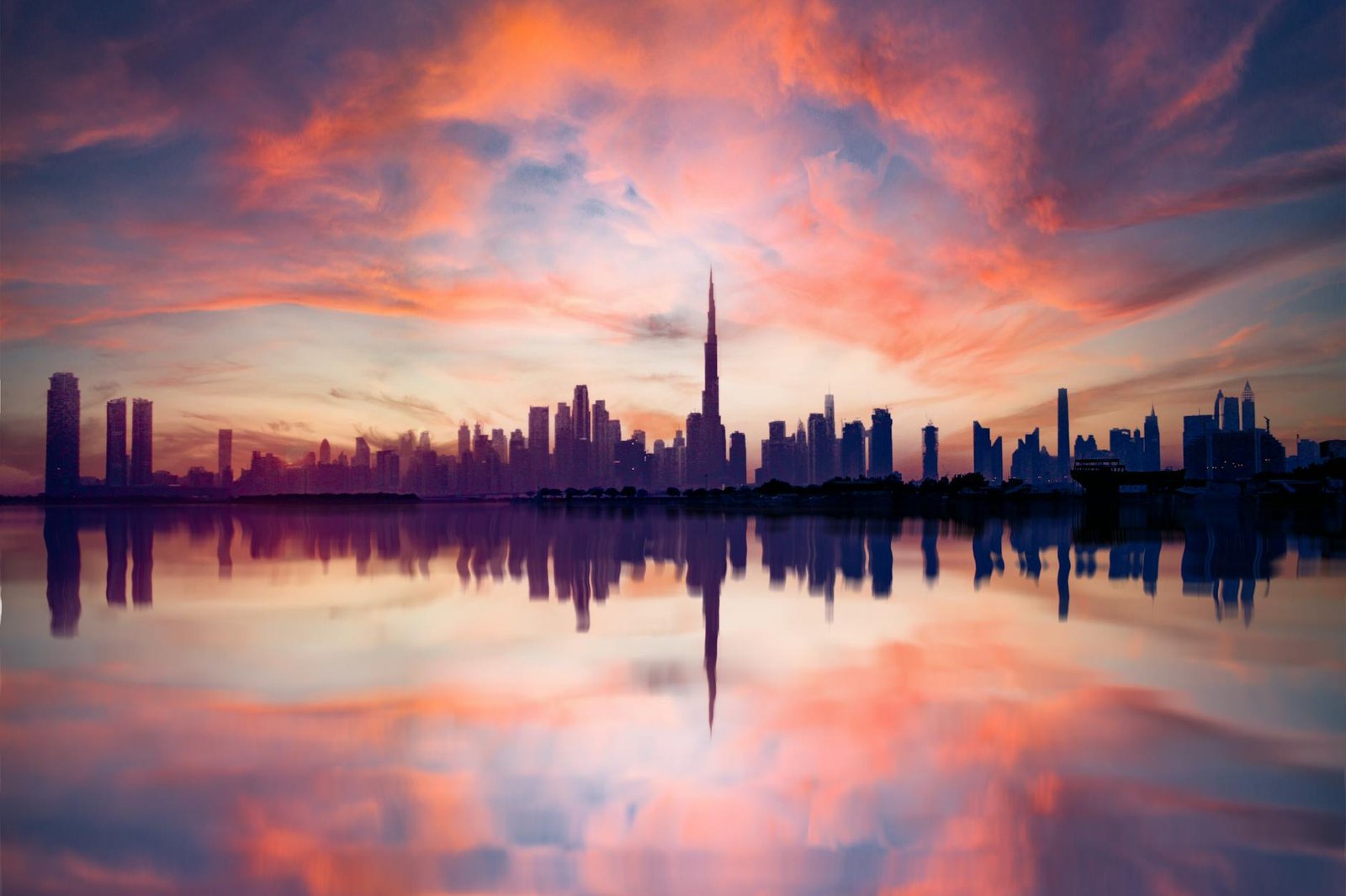 A breathtaking view of Dubai's skyline reflected in water during a vivid sunset, highlighting the urban architecture.