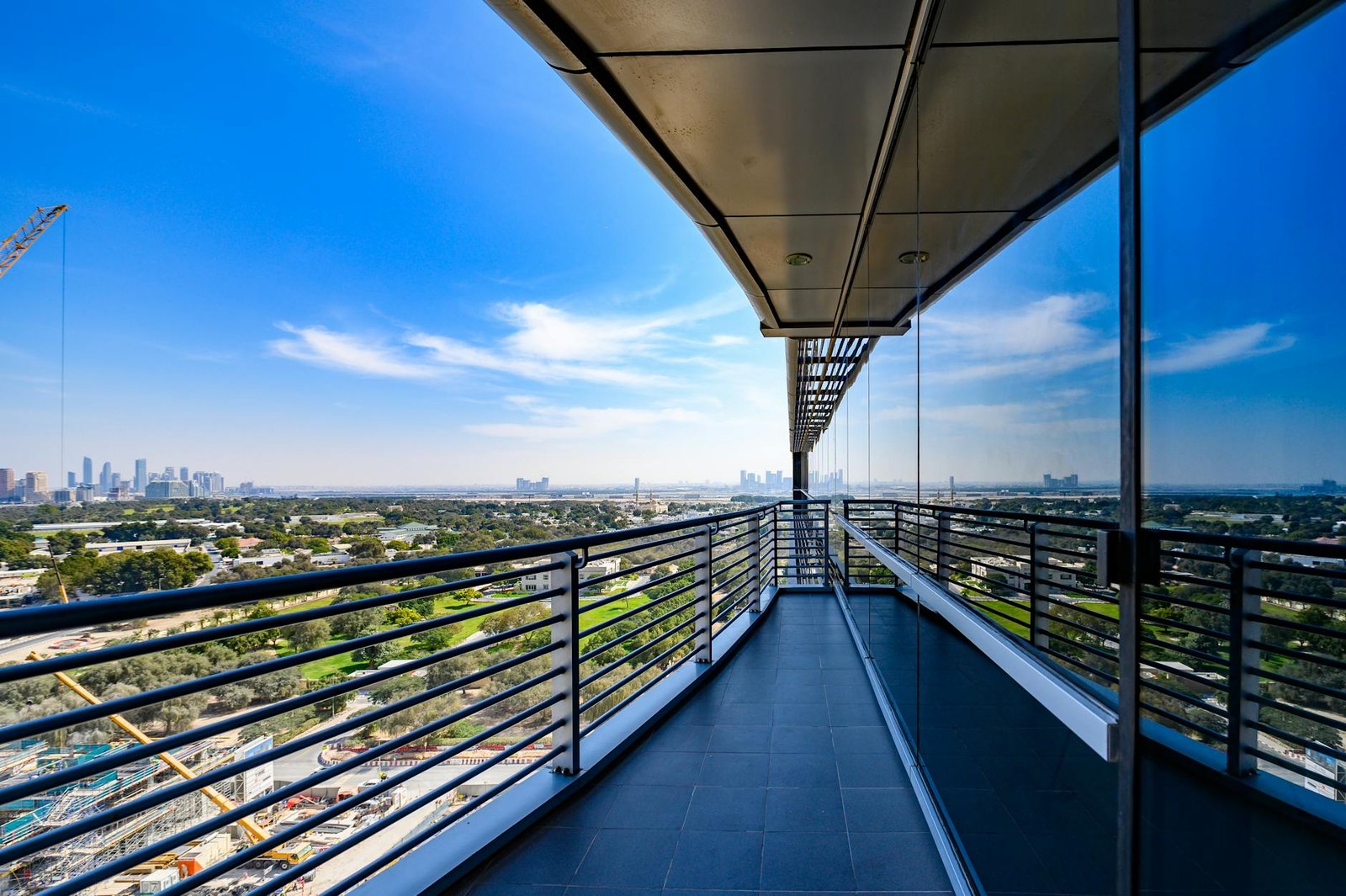 Sleek terrace with view of urban skyline and blue sky reflection on glass facade.