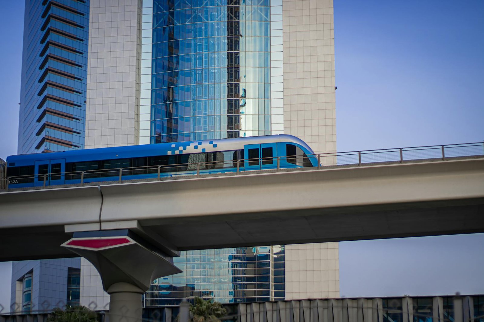 A sleek metro train passes high above a modern cityscape with tall glass skyscrapers.