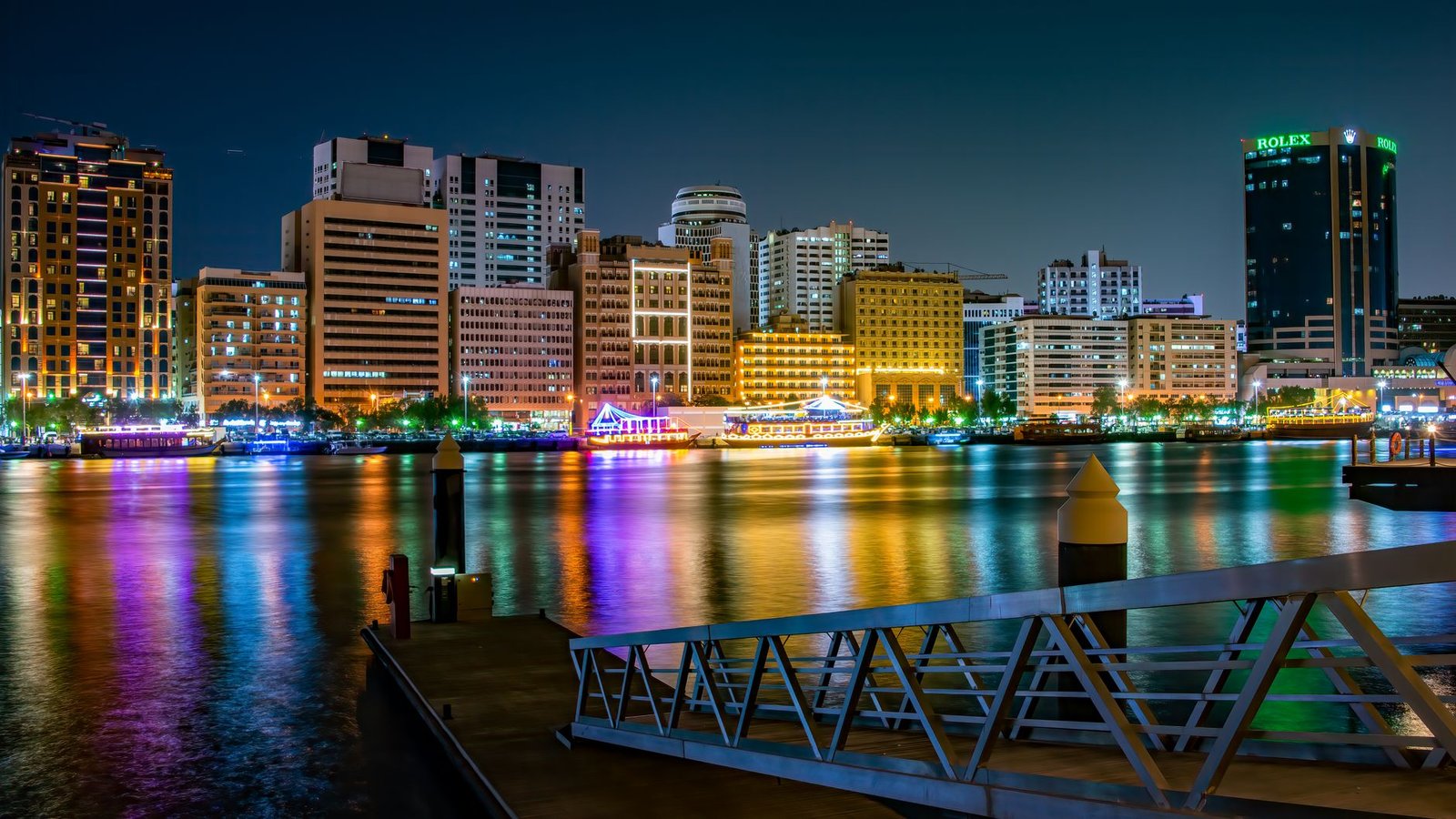 A stunning view of Dubai's illuminated skyline at night with colorful reflections on the waterfront.
