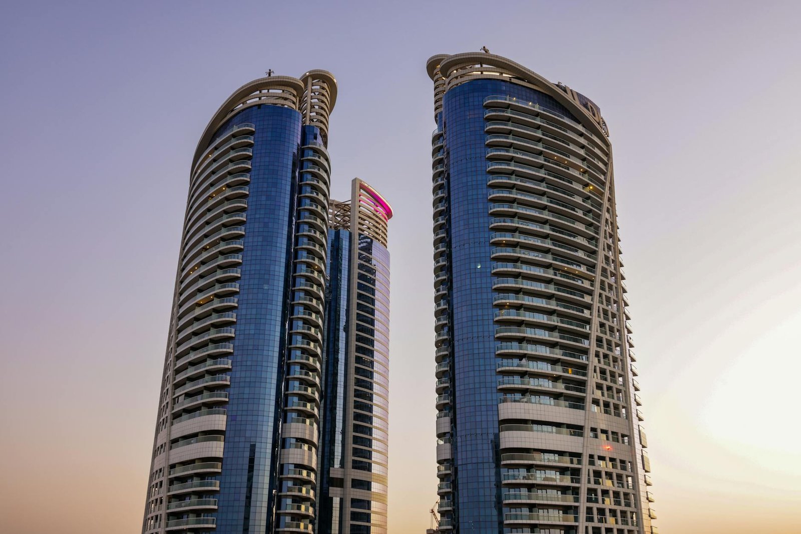 View of sleek modern skyscrapers in Dubai during sunset with clear sky.